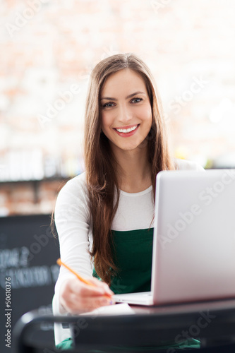 Photo: Young woman using laptop in cafe Young woman using laptop in cafe
