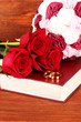 Wedding rings on bible with roses on wooden background