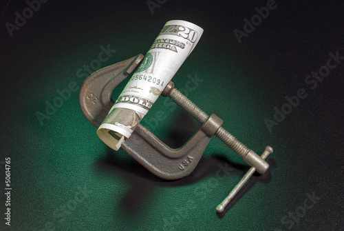 Photo: Money squeeze as a metaphor for inflation and increase in taxes Money squeeze as a metaphor for inflation and increase in taxes