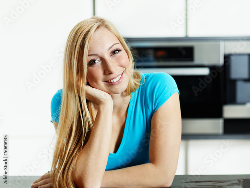 Photo: Relaxed young woman standing at the kitchen counter Relaxed young woman standing at the kitchen counter
