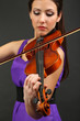 Beautiful young girl with violin on grey background
