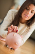 Young Woman Putting Coin In Piggybank