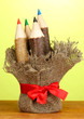 Colorful wooden pencils on wooden table on green background
