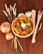 Appetizing village potatoes in bowl on wooden table close-up