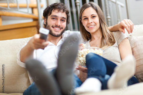 Photo: Couple watching tv in their living room at home Couple watching tv in their living room at home