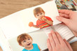 Photos in hands and photo album on wooden table