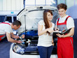 Car mechanics and customer look at the service record