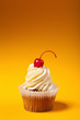 Photo: cupcake with red cherry isolated on orange background with copys cupcake with red cherry isolated on orange background with copys