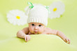 baby girl lying on green meadow among daisy