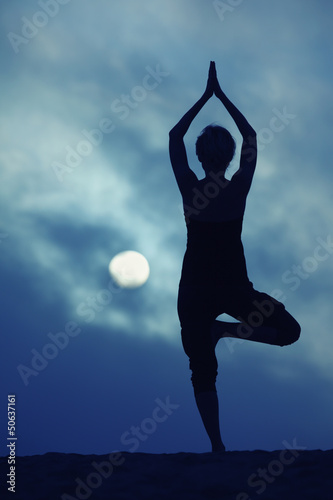 Photo: Woman in yoga Tree pose, full moon night Woman in yoga Tree pose, full moon night