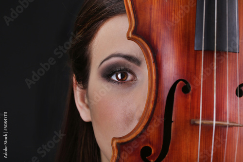 Photo: Beautiful young girl with violin on grey background Beautiful young girl with violin on grey background