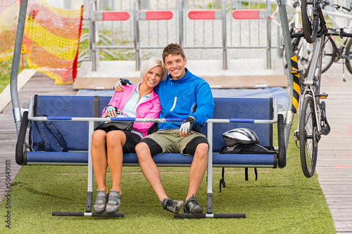 Photo: Cuddling couple sitting chair lift with bicycles Cuddling couple sitting chair lift with bicycles