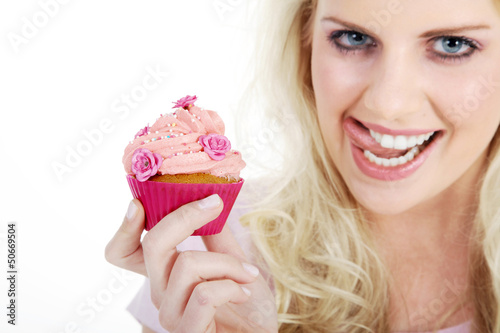 Photo: Junge hübsche Frau mit Cupcake leckt Mund Junge hübsche Frau mit Cupcake leckt Mund