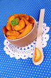 Appetizing village potatoes in bowl on blue fabric close-up
