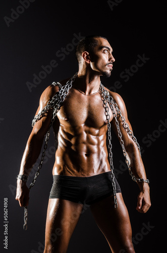 Photo: Muscular man with chain on black background Muscular man with chain on black background