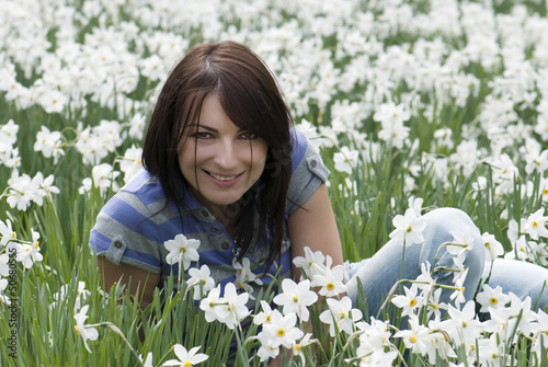Photo: Beautiful brunette sitting among daffodils Beautiful brunette sitting among daffodils