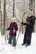 Smiling boy and his younger sister ski in winter park