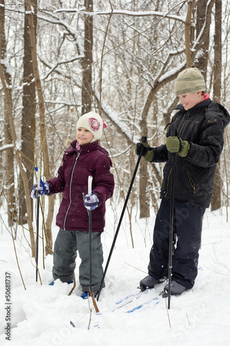 Photo: Smiling boy and his younger sister ski in winter park Smiling boy and his younger sister ski in winter park