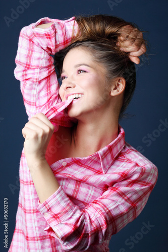 Photo: Beautiful pretty girl in pink plaid shirt holds hair Beautiful pretty girl in pink plaid shirt holds hair