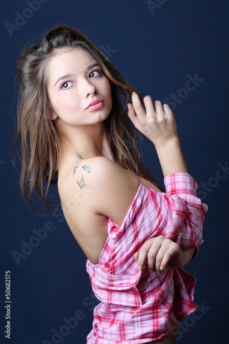 Photo: Beautiful smiling girl in removed in half pink plaid shirt looks Beautiful smiling girl in removed in half pink plaid shirt looks