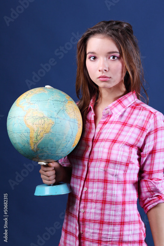 Photo: Serious and sad girl in plaid shirt holds desktop Globe. Serious and sad girl in plaid shirt holds desktop Globe.