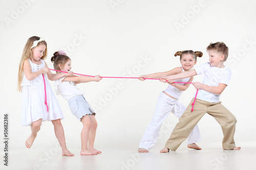 Photo: Four happy little boy and girls in white overtighten pink rope. Four happy little boy and girls in white overtighten pink rope.
