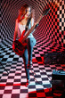 Happy girl plays red electric guitar and sings in studio