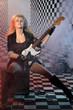 Photo: Young woman with electric guitar sits on the amplifier in studio Young woman with electric guitar sits on the amplifier in studio