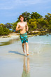 young boy with red hair jogging along the tropical beach