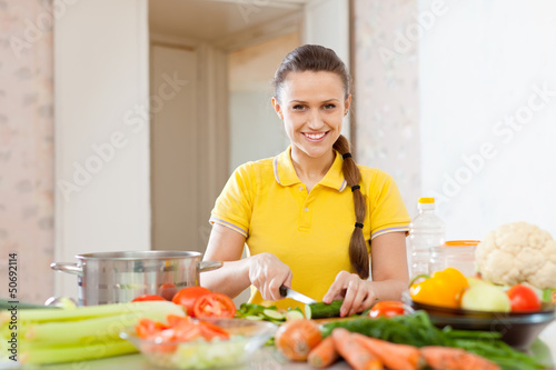 Photo: woman chopping vegetables at kitchen woman chopping vegetables at kitchen