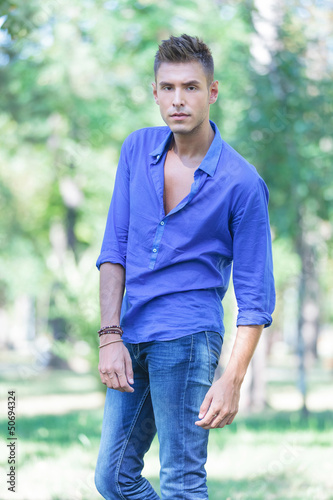 Photo: serious young man poses in park serious young man poses in park