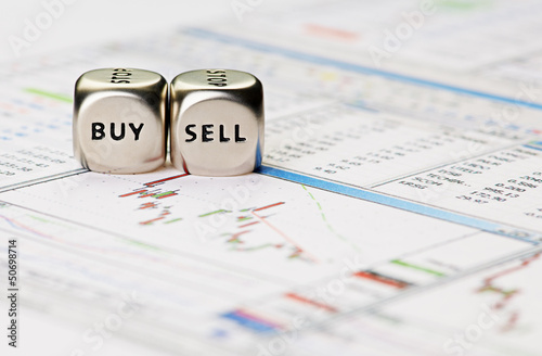 Photo: Dices cubes with the words SELL BUY on financial downtrend chart Dices cubes with the words SELL BUY on financial downtrend chart