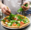 Closeup hand of chef baker in white uniform making pizza at kitc Closeup hand of chef baker in white uniform making pizza at kitc