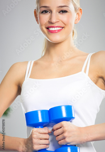 Photo: Young happy smiling woman with dumbbells, indoors Young happy smiling woman with dumbbells, indoors