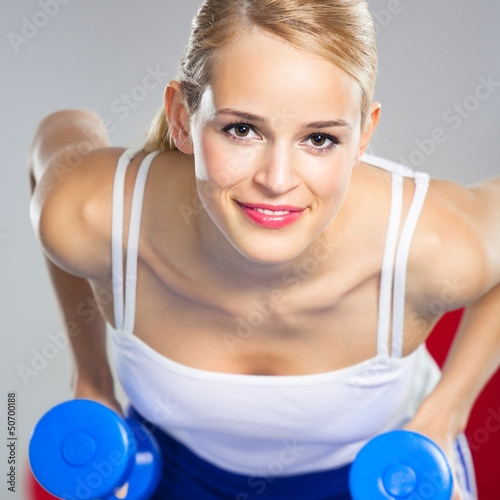 Photo: Young happy smiling woman with dumbbells, indoors Young happy smiling woman with dumbbells, indoors