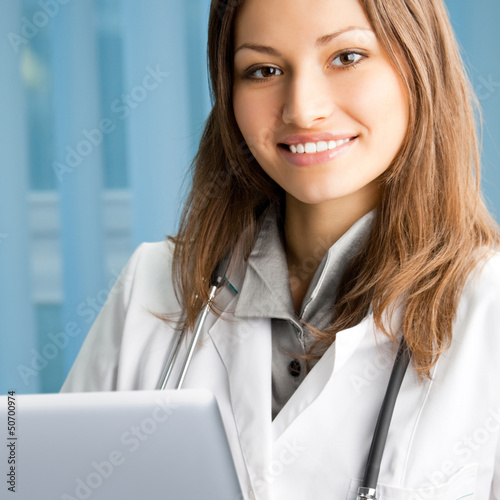 Photo: Cheerful female doctor with laptop Cheerful female doctor with laptop