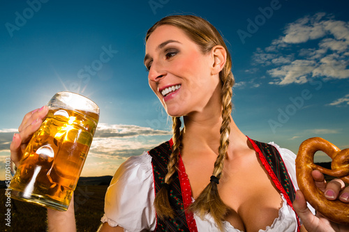 Photo: Frau trinkt Bier und hält Brezel in Bayern Tracht Frau trinkt Bier und hält Brezel in Bayern Tracht