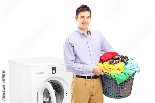 Photo: A smiling man with laundry bin posing next to a washing machine A smiling man with laundry bin posing next to a washing machine