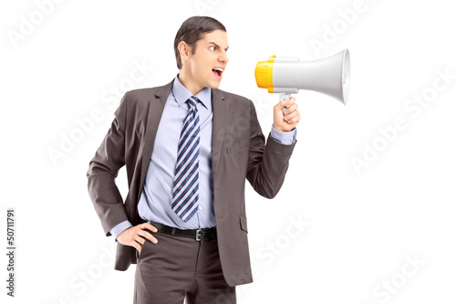 Photo: An angry young businessman announcing via megaphone An angry young businessman announcing via megaphone