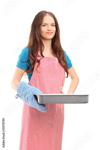 Photo: Beautiful woman with cooking mittens and apron holding a baking Beautiful woman with cooking mittens and apron holding a baking