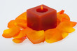 Spilt petals of the orange-rose around the aromatic candle