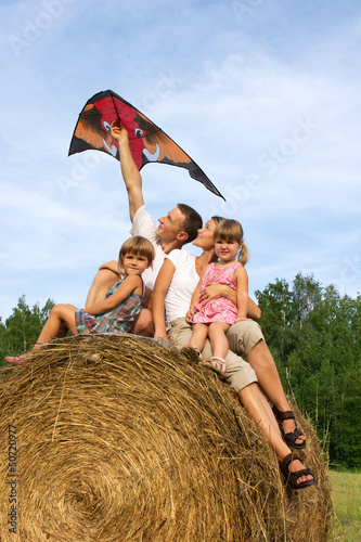 Photo: The happy family astride hay flying kite. The happy family astride hay flying kite.