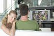 Photo: Portrait of young Caucasian woman with man watching movie on television in living room Portrait of young Caucasian woman with man watching movie on television in living room