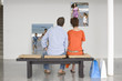 Photo: Rear view of couple seated on bench looking at photographs representing future planning Rear view of couple seated on bench looking at photographs representing future planning