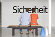 Photo: Rear view of couple reading German text "Sicherheit" (security) and contemplating about security Rear view of couple reading German text "Sicherheit" (security) and contemplating about security