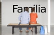 Photo: Rear view of couple seated on bench reading Spanish text "Familia" (family) on wall Rear view of couple seated on bench reading Spanish text "Familia" (family) on wall