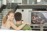 Photo: Portrait of young Caucasian woman with man watching movie on television in living room Portrait of young Caucasian woman with man watching movie on television in living room
