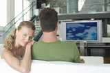Photo: Portrait of young Caucasian woman with man watching television in living room Portrait of young Caucasian woman with man watching television in living room