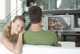 Photo: Portrait of young Caucasian woman with man watching movie on television in living room Portrait of young Caucasian woman with man watching movie on television in living room