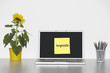 Photo: Sunflower plant on desk and sticky notepaper with Italian text on laptop screen saying "imposte" (Taxes) Sunflower plant on desk and sticky notepaper with Italian text on laptop screen saying "imposte" (Taxes)